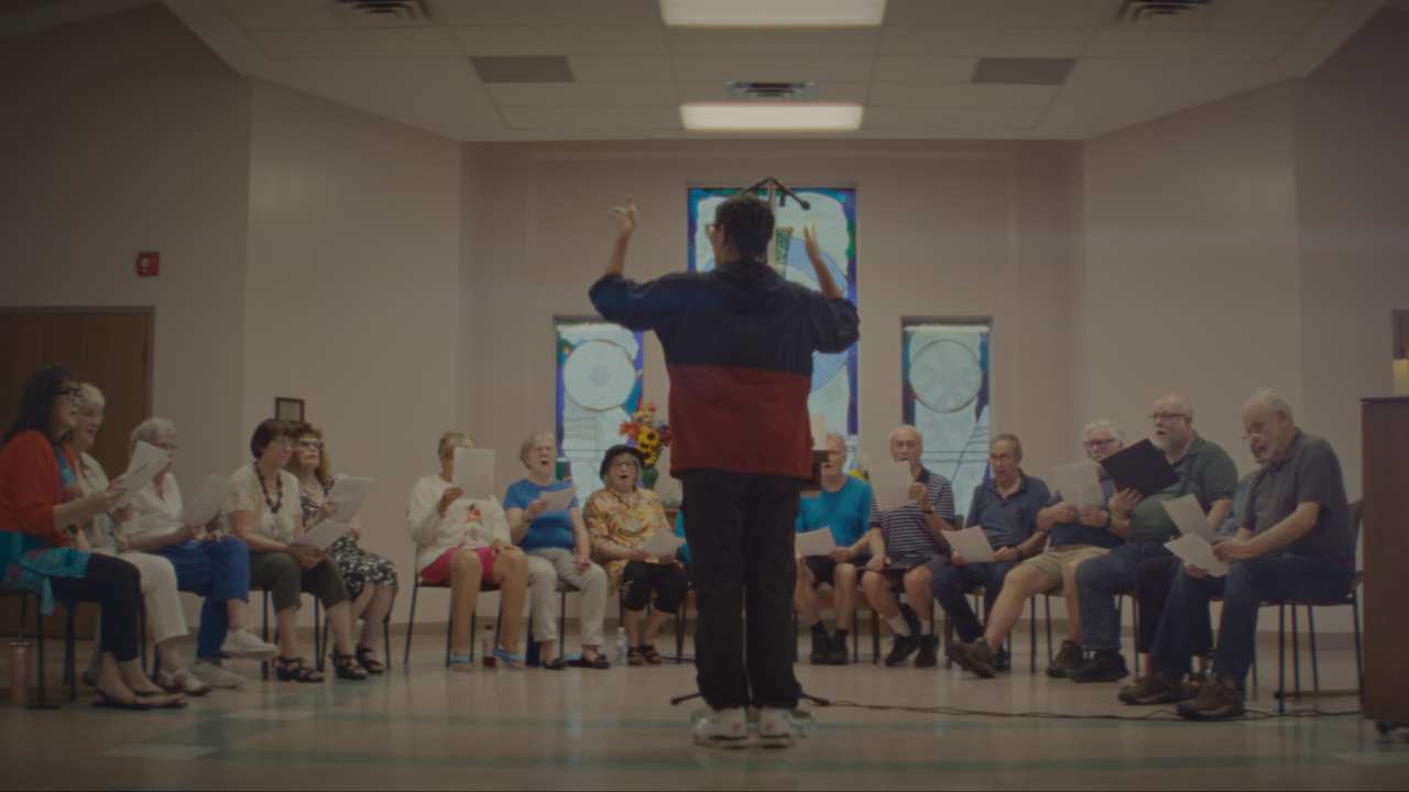 a person conducting a group of people singing